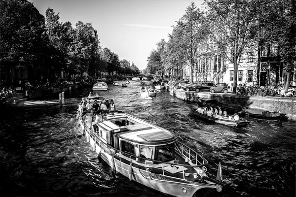 オランダ、アムステルダム - 2015 年 8 月 22 日: Veiw ボート、アムステルダムの運河の典型的な画像と川のチャネルを介して橋の上. — ストック写真