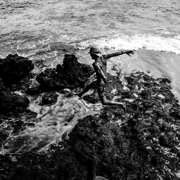 人 travaler 从海滩石头跳。黑呼呼的照片. — 图库照片