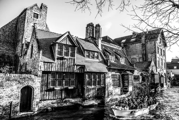 BRUGGE, BELGIUM - JANUARY 17, 2016: Transport boat with tourists which look on ancient building of medieval city on January 17, 2016 in Brugge - Belgium. — Stock Photo, Image