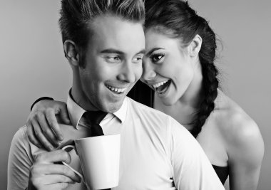 Young pair acquaintance. He holds a mug in his hands, she shows  clipart