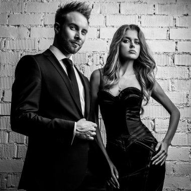 Portre studio poz genç çekici çift siyah moda kıyafetler giymiş. Siyah-beyaz fotoğraf.