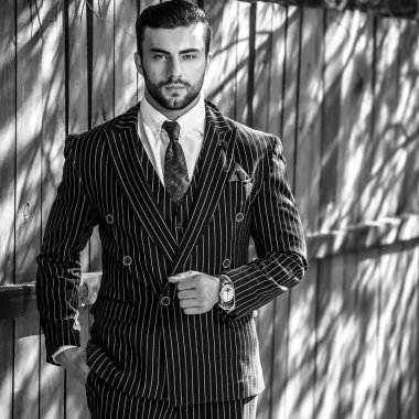 Klasik takım elbiseli ahşap çit karşı genç güzel şık adam portresi. Siyah-beyaz açık moda fotoğraf.