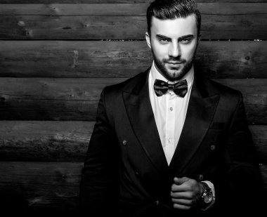 Siyah takım elbise ve kravat ahşap duvara karşı genç güzel şık adam portresi. Ahşap arka plan siyah-beyaz moda fotoğraf.