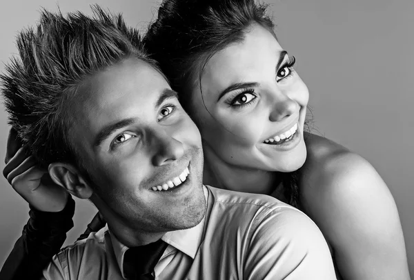 Fiatal vonzó & pozitív pár pózol a stúdió háttere. Fekete-fehér fénykép. — Stock Fotó