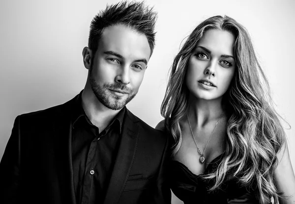 Portrait of young attractive couple posing studio dressed in black fashionable clothes. Black-white photo. Stock Picture