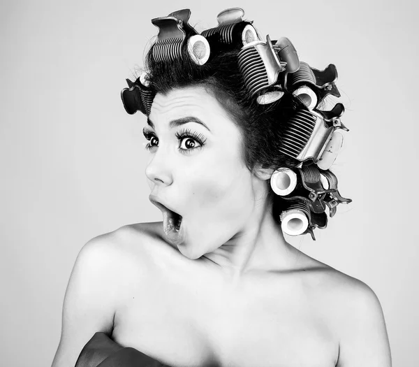 Emotional girl with hair-curlers on her head. Black-white studio photo. — Stock Photo, Image