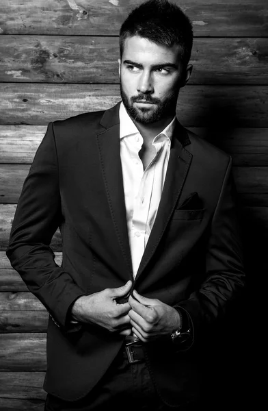 Ritratto in bianco-nero di giovane bellissimo uomo alla moda contro muro di legno . — Foto Stock