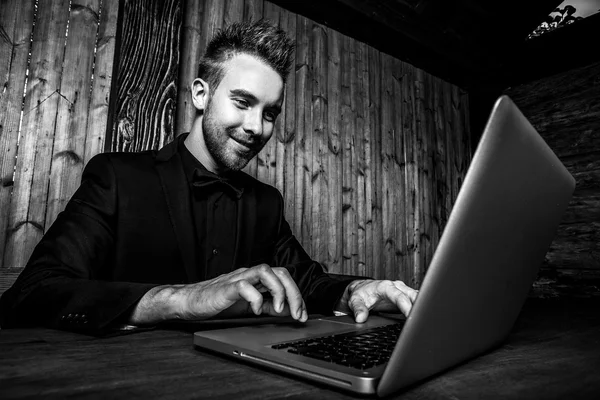 Retrato de joven hermoso hombre de moda contra la pared de madera En traje negro y corbata de lazo. Foto de moda blanco y negro sobre fondo de madera . — Foto de Stock