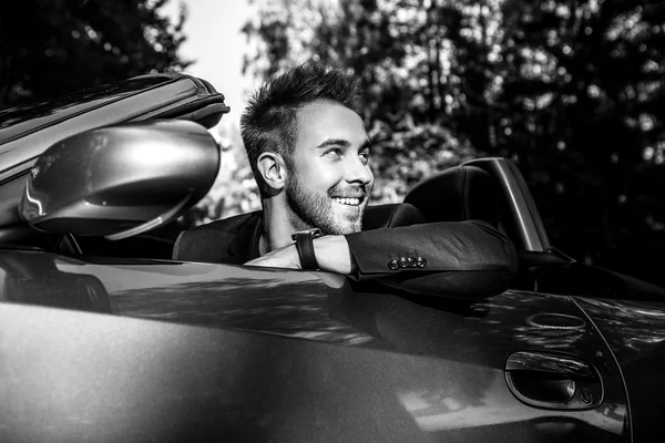 Élégant jeune homme à la mode en voiture décapotable en plein air. Portrait noir-blanc . — Photo