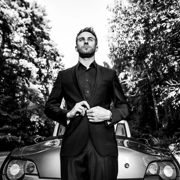 Élégant jeune homme à la mode en voiture décapotable en plein air. Portrait noir-blanc . — Photo