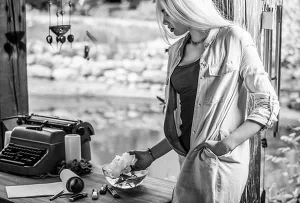 Black-white outdoors photo of beautiful young blonde in arbor at oak table near vintage typewriter. — Stock Photo, Image