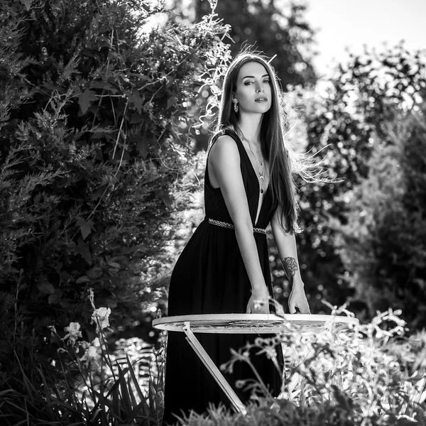 Preto-branco ao ar livre retrato de bela jovem mulher em vestido elegante posando no jardim de verão . — Fotografia de Stock