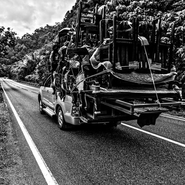 Перегруженный домами пикап движется по горной дороге
.