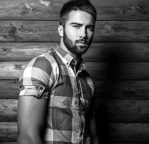 Retrato blanco y negro de joven hermoso hombre de moda contra la pared de madera . — Foto de Stock