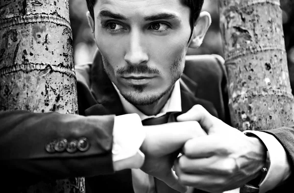 Close-up portrait of young serious handsome man in classic costume outdoors. Black-white photo. — Stock Photo, Image