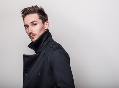Uzun şık koyu mavi ceket zarif genç yakışıklı adam. Studio moda portre.