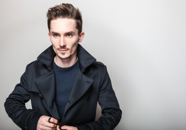 Uzun şık koyu mavi ceket zarif genç yakışıklı adam. Studio moda portre.