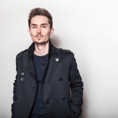 Uzun şık koyu mavi ceket zarif genç yakışıklı adam. Studio moda portre.