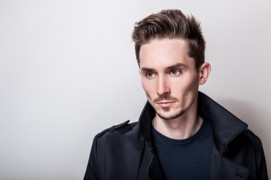 Uzun şık koyu mavi ceket zarif genç yakışıklı adam. Studio moda portre.