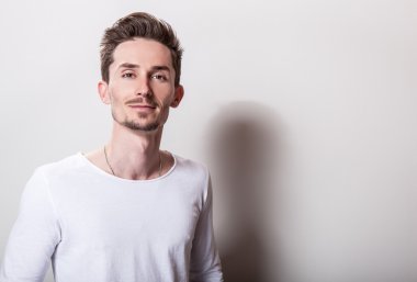 Stüdyo portre rahat basit beyaz t-shirt genç yakışıklı adamın.
