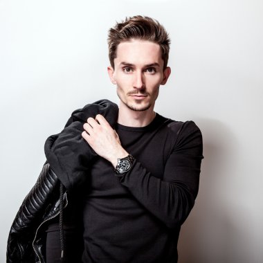 Siyah t-shirt ve deri ceket ışık gri stüdyo arka plan üzerinde poz onun elinde çekici şık adam.