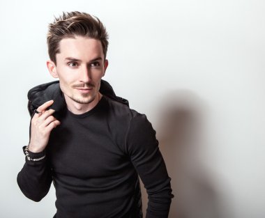 Siyah t-shirt ve deri ceket ışık gri stüdyo arka plan üzerinde poz onun elinde çekici şık adam.