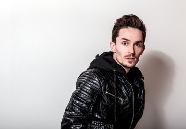 Işık gri arka plan üzerinde poz şık siyah deri ceketli çekici şık adamı.