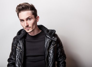 Işık gri arka plan üzerinde poz şık siyah deri ceketli çekici şık adamı.