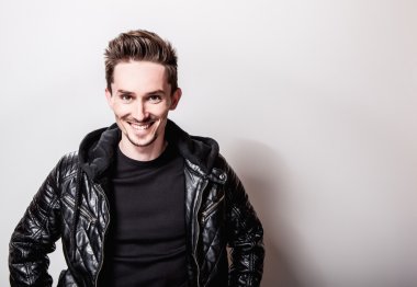 Işık gri arka plan üzerinde poz şık siyah deri ceketli çekici şık adamı.