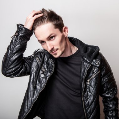 Işık gri arka plan üzerinde poz şık siyah deri ceketli çekici şık adamı.