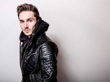 Işık gri arka plan üzerinde poz şık siyah deri ceketli çekici şık adamı.