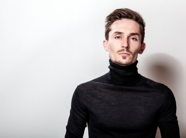 Çekici şık erkek siyah Golf ışık gri arka plan üzerinde poz.