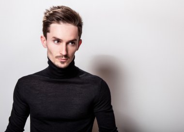 Çekici şık erkek siyah Golf ışık gri arka plan üzerinde poz.