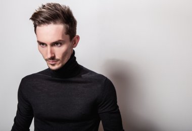 Çekici şık erkek siyah Golf ışık gri arka plan üzerinde poz.