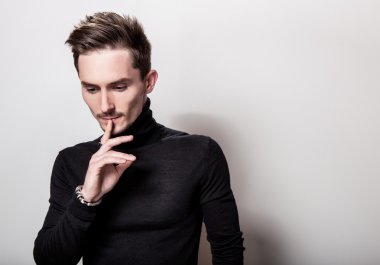 Çekici şık erkek siyah Golf ışık gri arka plan üzerinde poz.