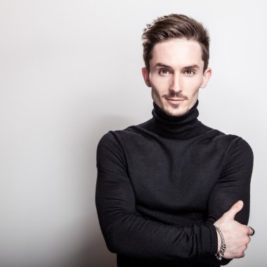 Çekici şık erkek siyah Golf ışık gri arka plan üzerinde poz.