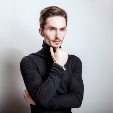 Çekici şık erkek siyah Golf ışık gri arka plan üzerinde poz.