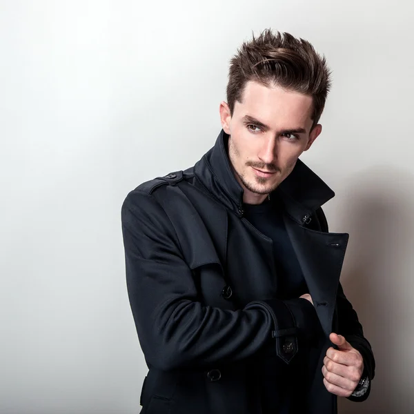 Elegante homem bonito jovem em casaco azul escuro elegante longo. Estúdio retrato de moda . — Fotografia de Stock