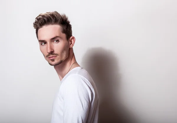 Studioporträt eines jungen gutaussehenden Mannes in lässigem, schlichten weißen T-Shirt. — Stockfoto