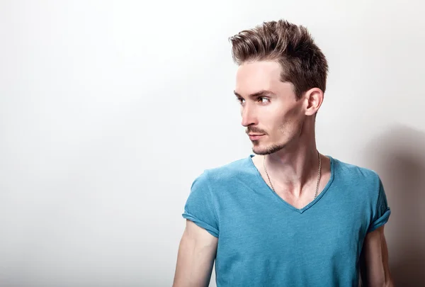 Retrato de estudio de un joven guapo en una camiseta casual de color turquesa . — Foto de Stock