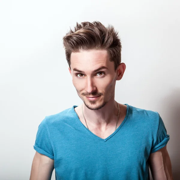 Retrato de estudio de un joven guapo en una camiseta casual de color turquesa . — Foto de Stock