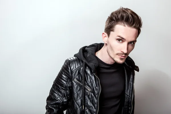 Attractive elegant man in stylish black leather jacket posing on light gray background. — Stock Photo, Image