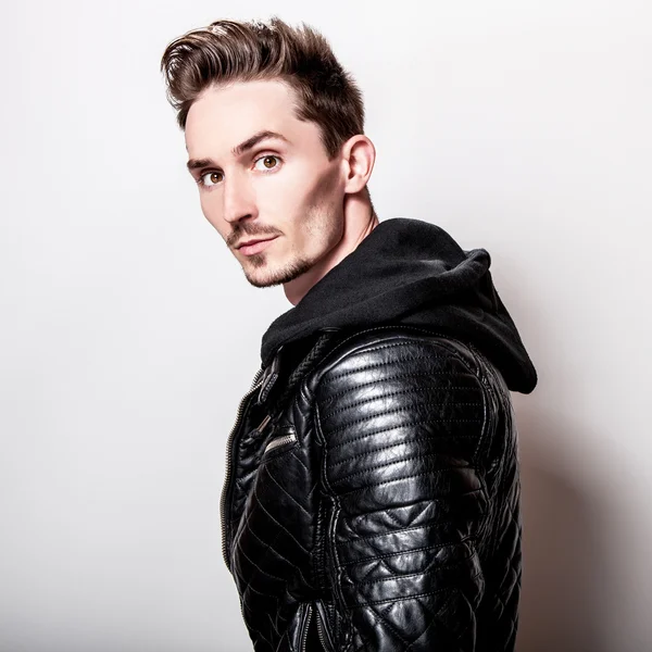 Işık gri arka plan üzerinde poz şık siyah deri ceketli çekici şık adamı.