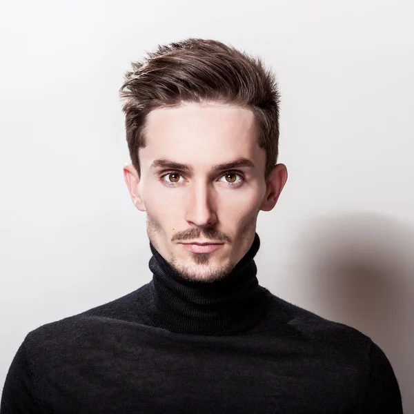 Çekici şık erkek siyah Golf ışık gri arka plan üzerinde poz.