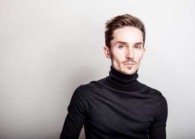 Çekici şık erkek siyah Golf ışık gri arka plan üzerinde poz.