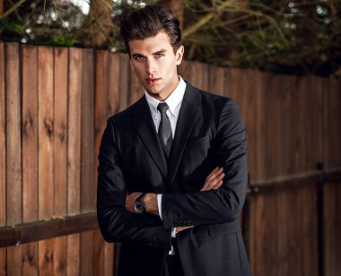 Klasik takım elbise teşkil ahşap çit yakınındaki zarif yakışıklı adam