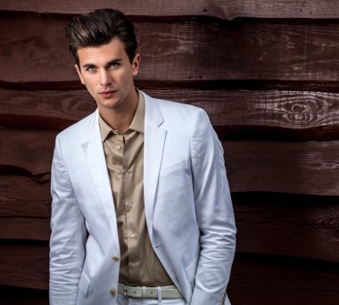 Ahşap duvara yaslanmış genç ve şık bir adamın portresi.