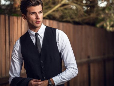 Klasik takım elbise teşkil ahşap çit yakınındaki zarif yakışıklı adam