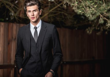 Klasik takım elbise teşkil ahşap çit yakınındaki zarif yakışıklı adam