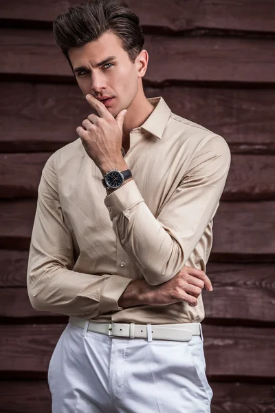 Portrait of young beautiful fashionable man against wooden wall — Stock Photo, Image